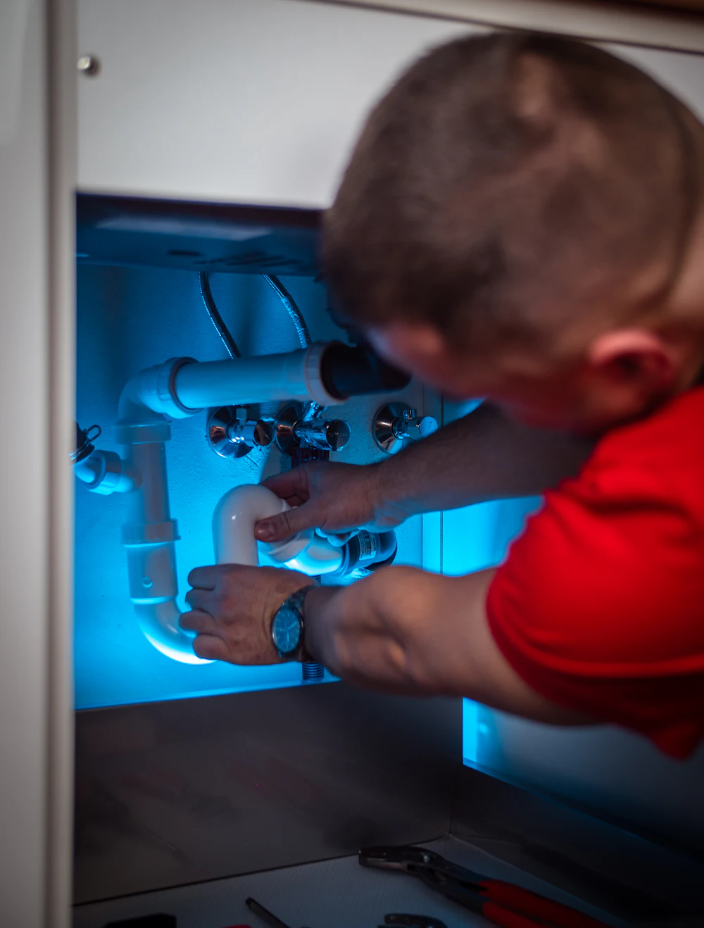 Technician fitting RO water purifier pipes under kitchen sink